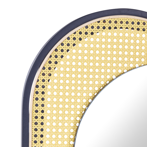 Ovaler Spiegel mit Rattanrahmen hängt an der Wand über einem Sessel und einem Beistelltisch.