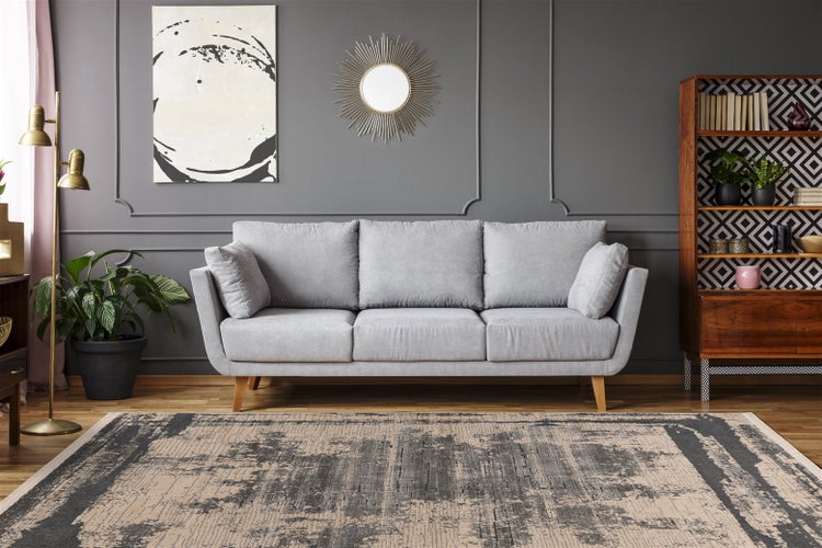 Nahaufnahme eines grau-beigen Teppichs mit abstraktem Muster und strukturierter Oberfläche.