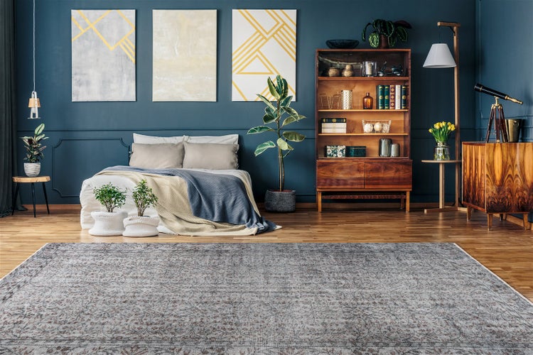 Großer Teppich mit Vintage-Muster in einem Schlafzimmer mit Holzmöbeln, Wandbildern und einer Zimmerpflanze.