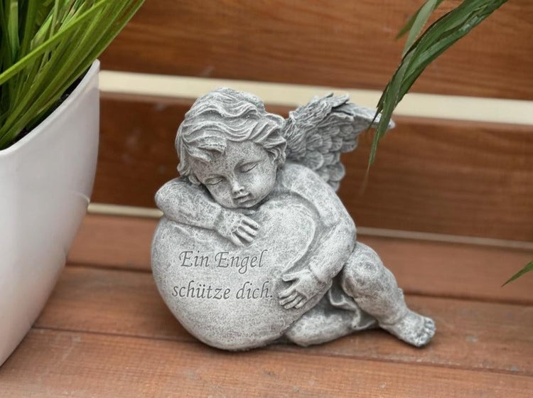 Dekorative Engelsfigur aus Stein mit Herz und Inschrift Ein Engel schütze dich als Grabschmuck oder Gartendekoration.