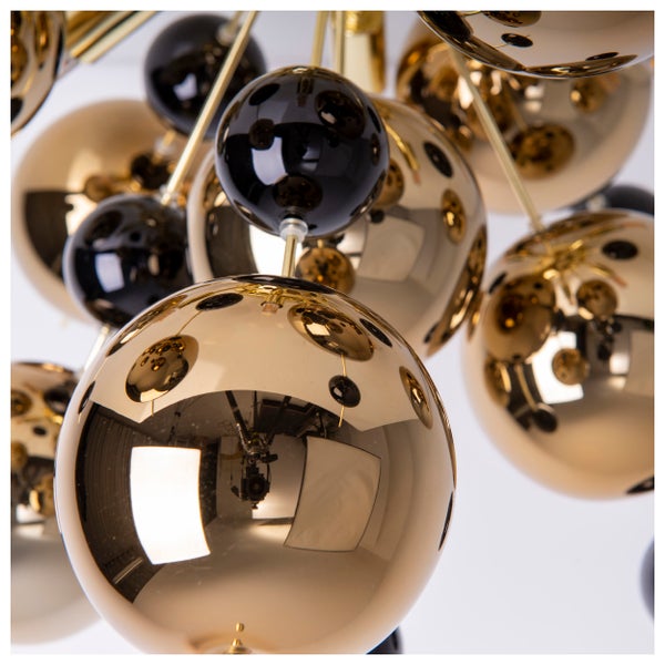 Nahaufnahme einer Hängeleuchte mit goldenen und schwarzen Kugeln.
