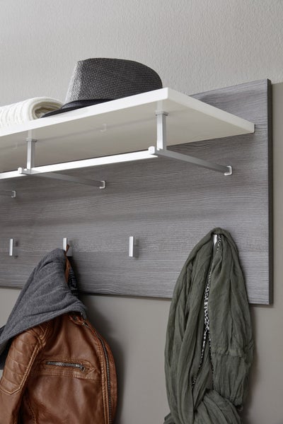 Wandgarderobe mit grauer Holzrückwand, weißer Hutablage, einer Kleiderstange aus Metall und mehreren Haken.