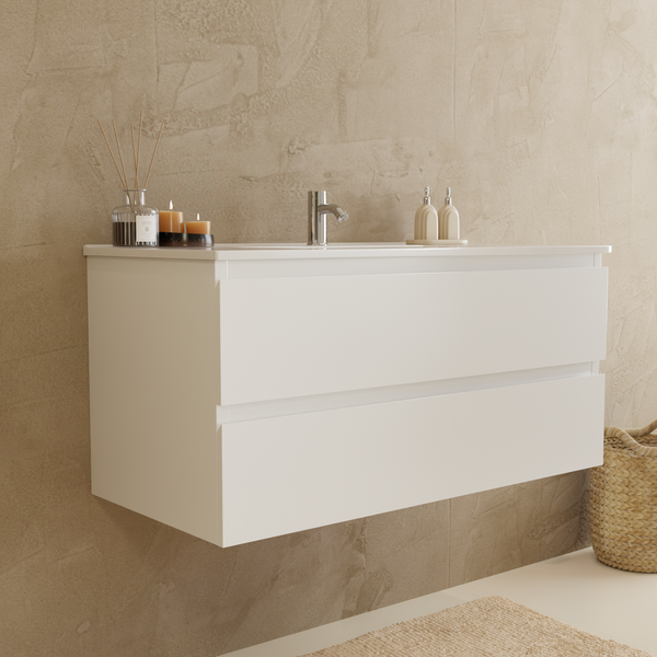 Hängender Waschtischunterschrank mit zwei Schubladen und aufgesetztem Waschbecken an einer strukturierten Wand in einem modernen Badezimmer.