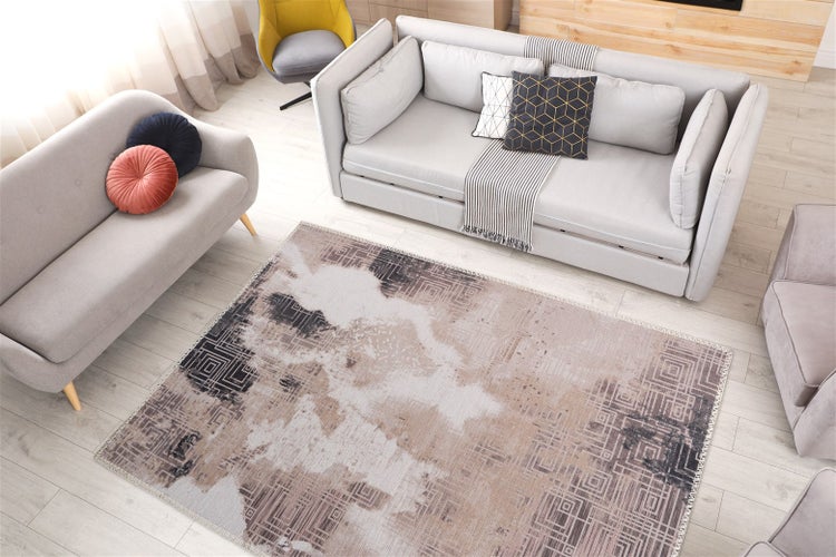 Moderner Wohnbereich mit zwei grauen Sofas und einem großen Teppich mit abstraktem geometrischem Muster auf hellem Boden.