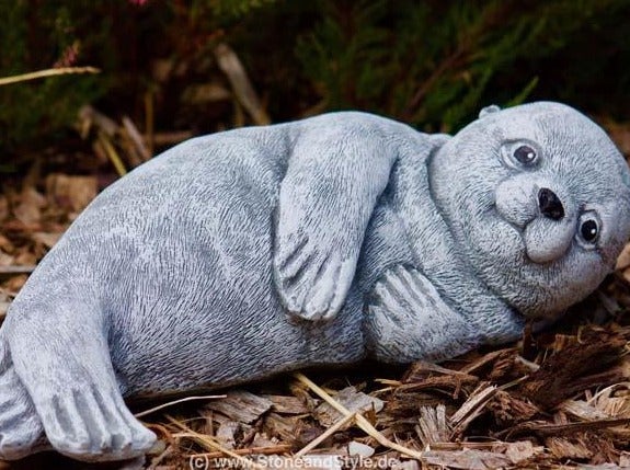 Gartenfigur in Form einer liegenden Robbe aus witterungsbeständigem Steinguss zur Dekoration im Außenbereich.