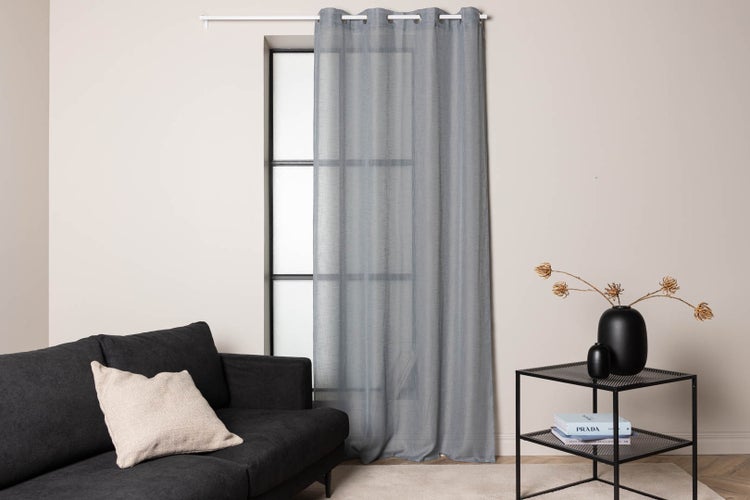 Szene mit einem grauen Vorhang an einem Fenster, einer Couch und einem Beistelltisch mit Dekoration