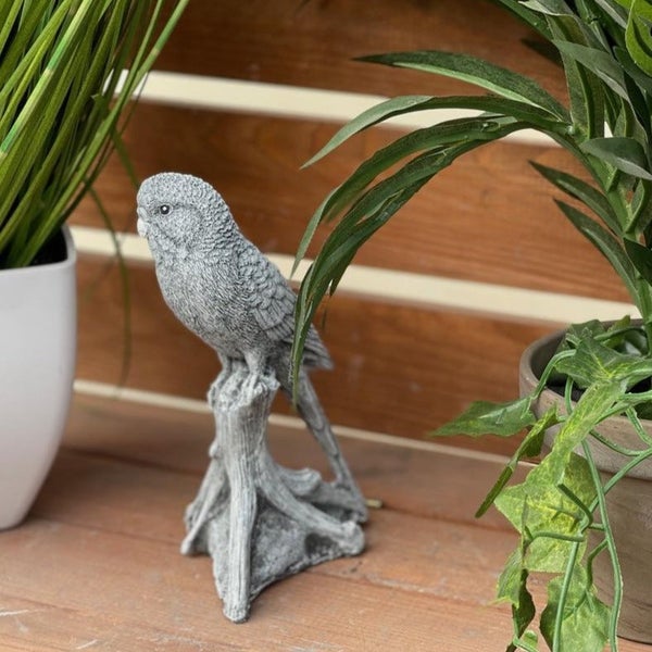 Dekorative Wellensittich Gartenfigur aus Stein auf einem Baumstamm stehend als Garten- oder Balkondekoration