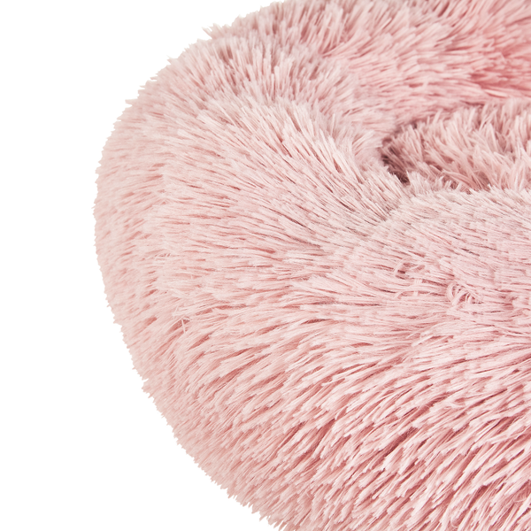 Detailaufnahme eines runden, flauschigen Haustierbetts aus rosa Kunstfell.