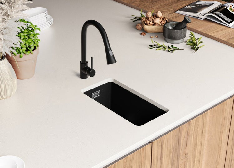 Küchenszene mit Spüle, Armatur und dekorativen Elementen auf einer Arbeitsplatte.