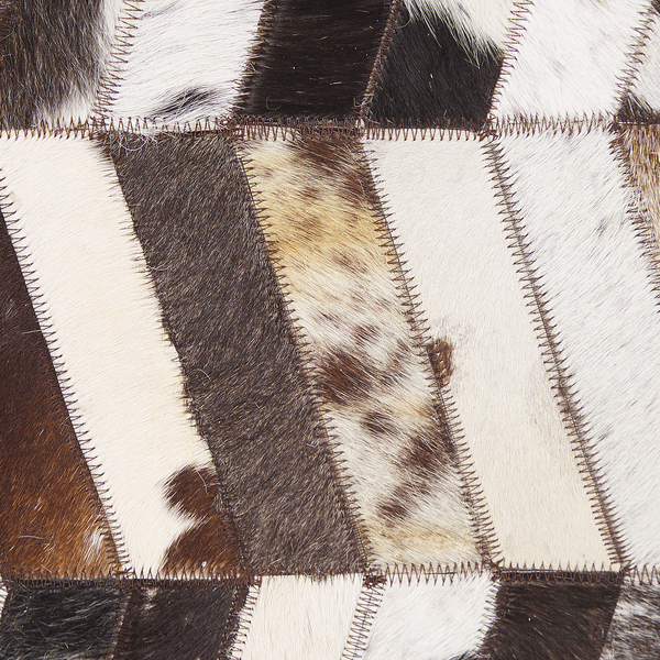 Teppich aus zusammengesetzten Fellstreifen mit markanten Ziernähten im Patchwork Design.