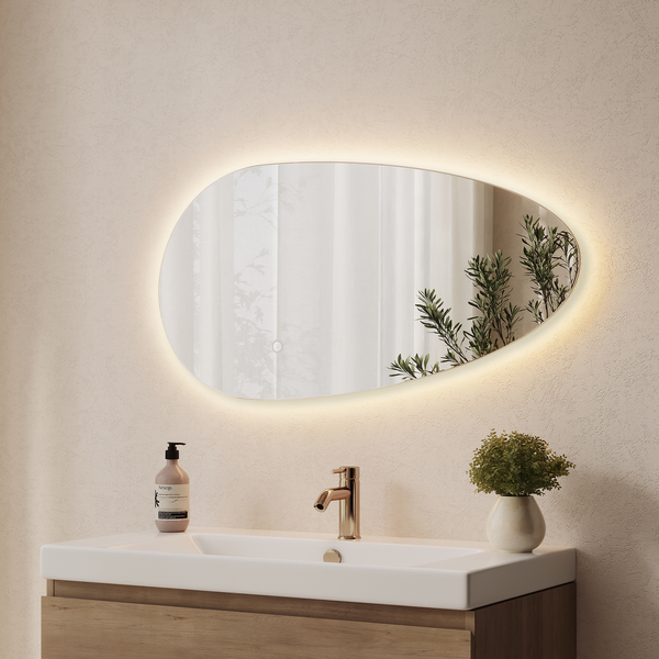 Organisch geformter Wandspiegel mit integrierter LED Beleuchtung über einem Waschbecken mit Armatur und Holzwaschtischunterschrank.