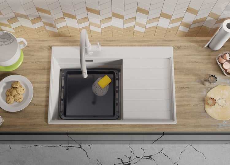 Küchenszene mit Spüle, Backblech, Spülschwamm und Backutensilien auf einer Arbeitsplatte