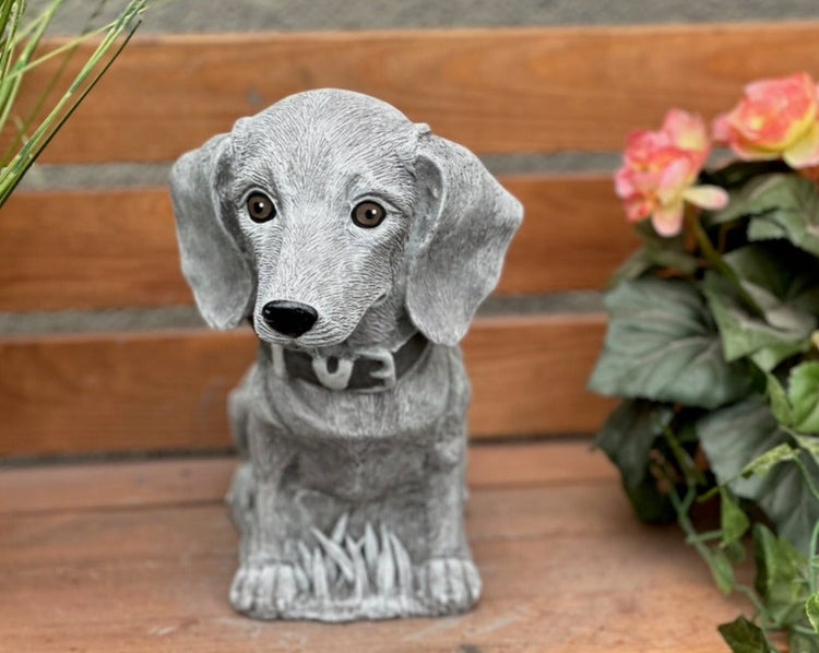 Gartenfigur in Form eines sitzenden Hundes aus Steinguss, detailreiche Nachbildung eines Dackels mit Halsband für Garten und Terrasse.