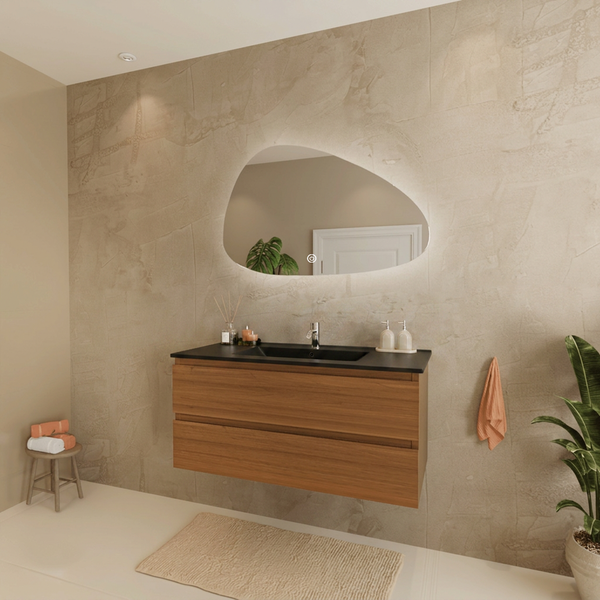 Modernes Badezimmer mit schwebendem Holz-Waschtisch, schwarzem Waschbecken und organisch geformtem, beleuchtetem Spiegel an strukturierter Wand.