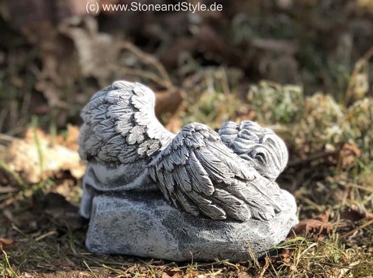 Steinfigur schlafender Engel auf einem Fels als Dekoration für den Garten