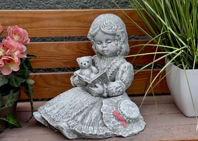 Gartenfigur aus Steinguss in Form eines Mädchens, das einem Teddybären aus einem Buch vorliest, detailreiche Dekoration für den Garten.