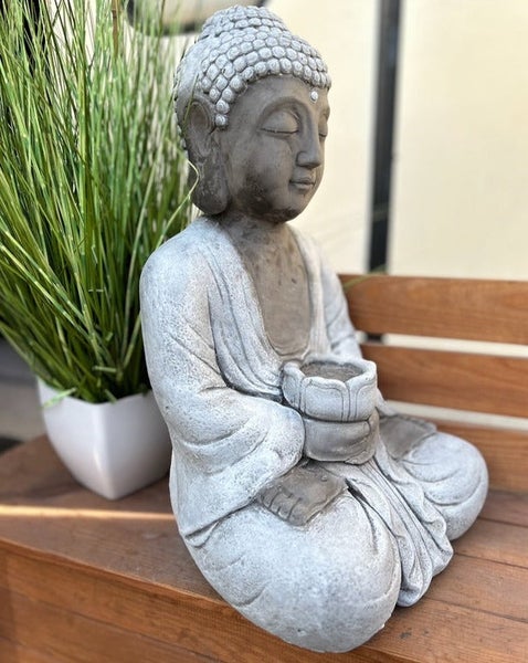 Sitzende Buddha-Figur in Steinoptik, eine Schale in den Händen haltend, dekorative Gartenfigur.