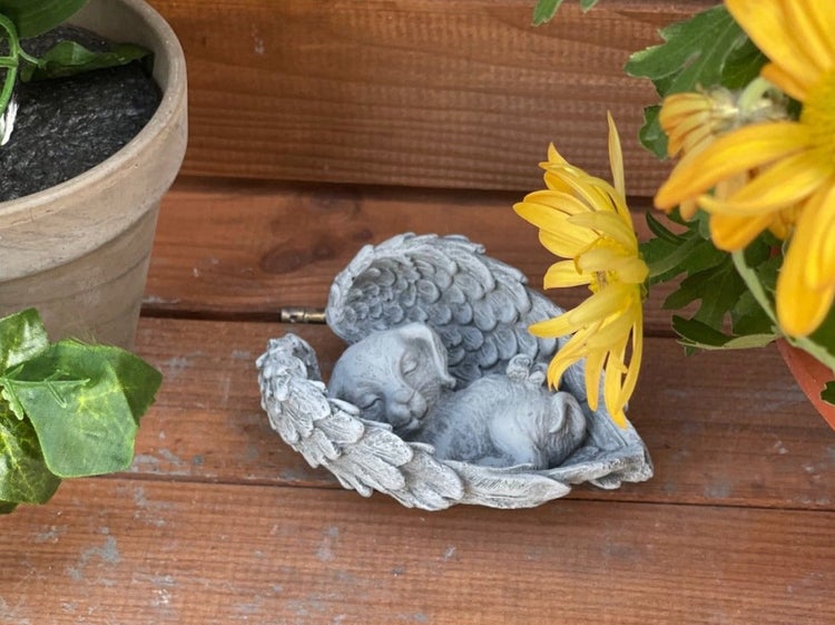 Grabfigur Hund als schlafendes Engelchen aus Kunststein für den Garten als Dekoration.
