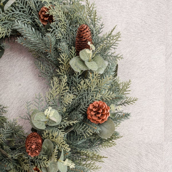 Dekorativer Türkranz mit Tannenzapfen und künstlichen Pflanzen für festliche Stimmung