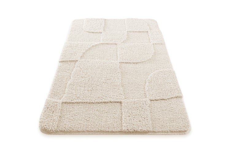 Cremefarbene Badematte mit geometrischem Hoch-Tief-Muster und abgerundeten Ecken.