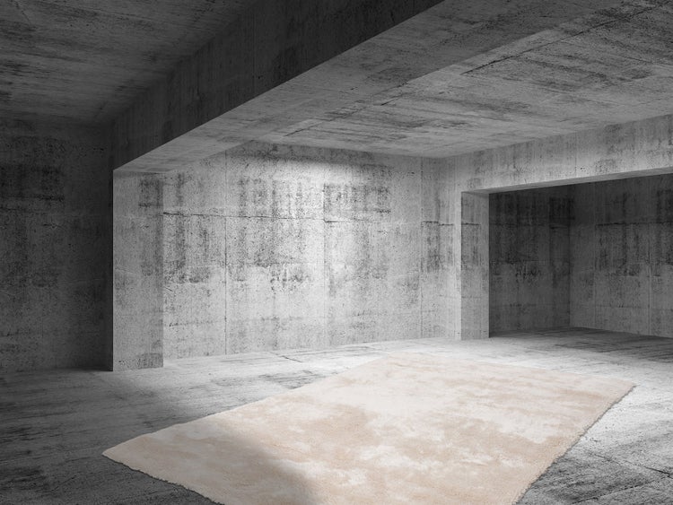 Hochflor-Teppich in hellem Beige in einem weitläufigen, industriellen Raum mit Wänden und Boden aus Sichtbeton.