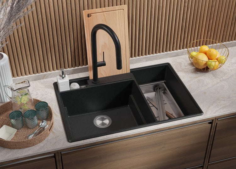Schwarze Küchenspüle mit Armatur, Schneidebrett und Abtropfkorb auf einer Küchentheke