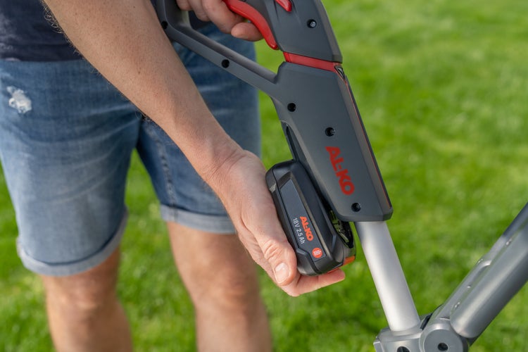 Eine Hand setzt einen AL-KO 18 Volt 2,5 Amperestunden Akku in ein AL-KO Gartengerät ein.