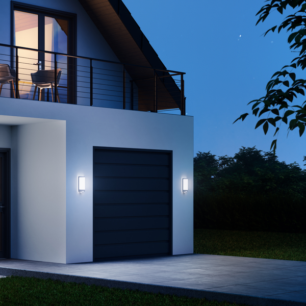 Moderne Außenwandleuchten an einem Haus mit Garage bei Nacht.