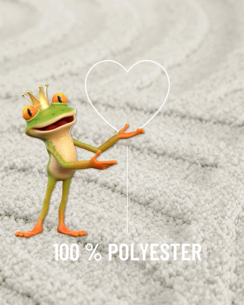 Frosch mit Krone und Herzsymbol auf einem Teppich mit dem Hinweis 100 Prozent Polyester.