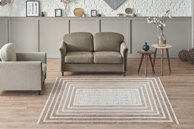 Helles, organisiertes Wohnzimmer mit geometrisch gemustertem Teppich, beige gepolstertem Sofa und Sessel auf Holzfußboden mit Wanddekoration.