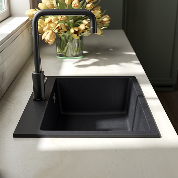 Moderne schwarze Einbauspüle aus Verbundwerkstoff mit passender hoher Küchenarmatur in einer hellen Küchenarbeitsplatte mit Blumenstrauß