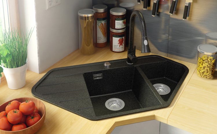 Eckspüle aus Granit mit Abtropffläche und Armatur in einer hellen Küche.