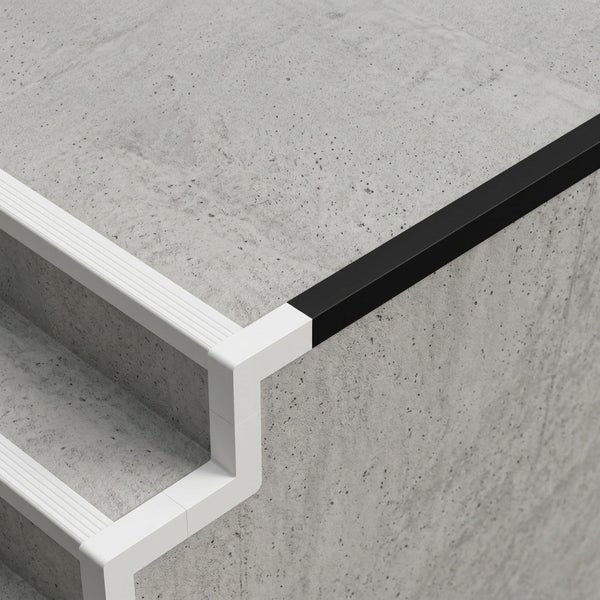 Treppenkantenprofil mit Eckverbinder in Weiß und Schwarz auf Stufen in Betonoptik.