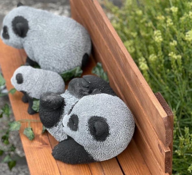 Drei Panda Gartenfiguren aus Stein auf einer hölzernen Bank im Außenbereich.