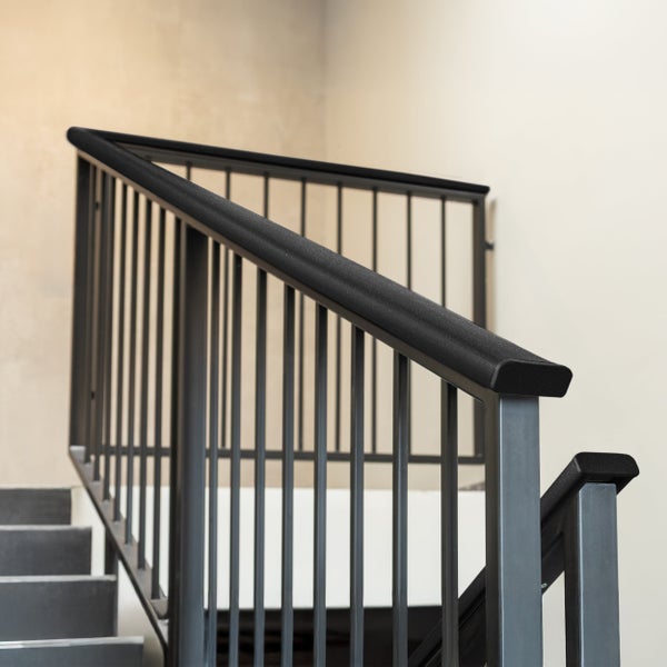 Treppengeländer aus Metall mit schwarzem Handlauf und vertikalen Stäben an einer Treppe.