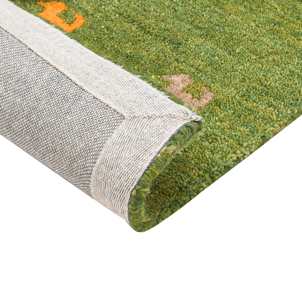 Detailansicht eines grünen Teppichs mit floralem Muster und gewebter Unterseite