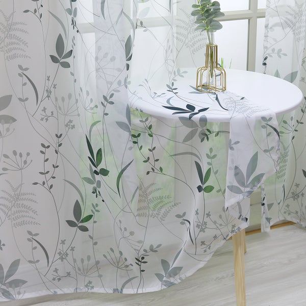 Dekorative Fenstergardine mit Blattmuster und rundem Tisch mit Blumenvase