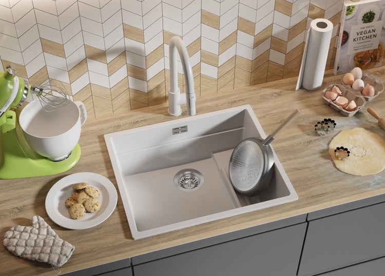 Küchenszene mit Spüle, Armatur und Küchenutensilien auf einer Arbeitsplatte.