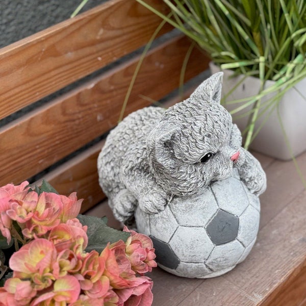 Gartenfigur Katze auf einem Fußball als dekoratives Element für Außenbereiche aus wetterfestem Material.