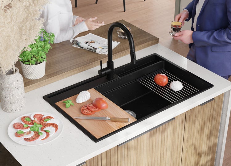 Küchenszene mit schwarzem Spülbecken, Armatur und kulinarischen Vorbereitungen auf einer hellen Arbeitsplatte.