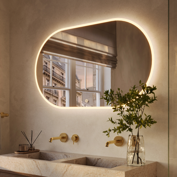 Ovaler LED Wandspiegel mit indirekter Beleuchtung über einem Doppelwaschtisch mit goldenen Armaturen im Badezimmer