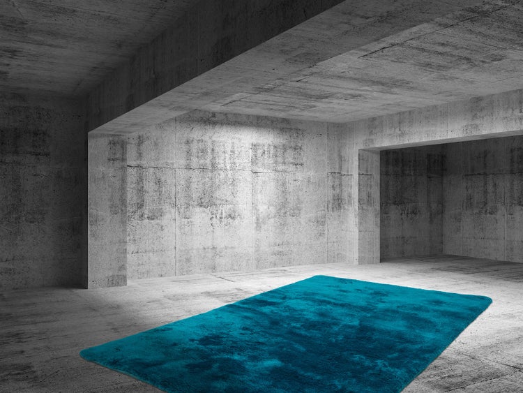 Türkiser Hochflor-Teppich in einem weitläufigen industriellen Raum mit Wänden und Boden aus Beton.