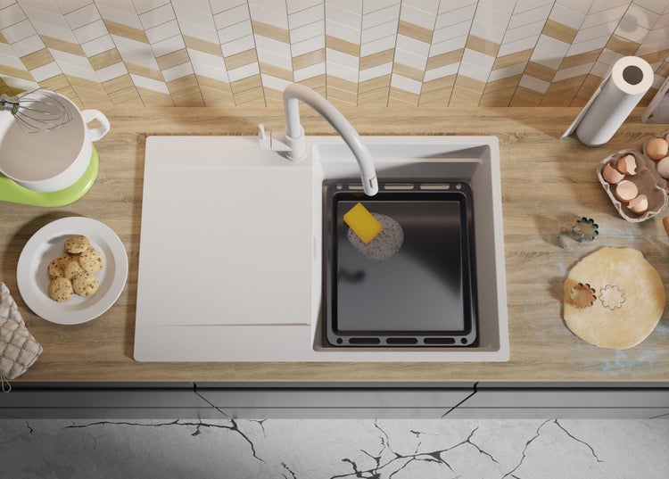 Küchenspüle mit Backblech, Spülmittel und Küchenutensilien auf einer Küchentheke.