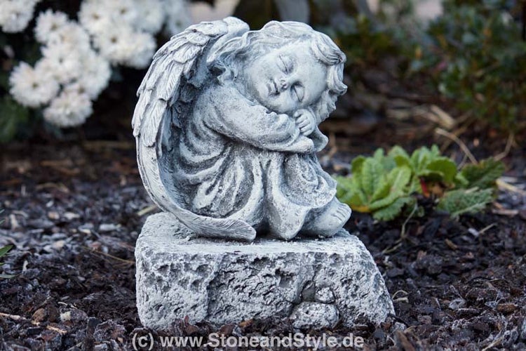 Grabfigur oder Gartenfigur in Form eines schlafenden Engels aus Steinguss auf einem rechteckigen Sockel stehend.
