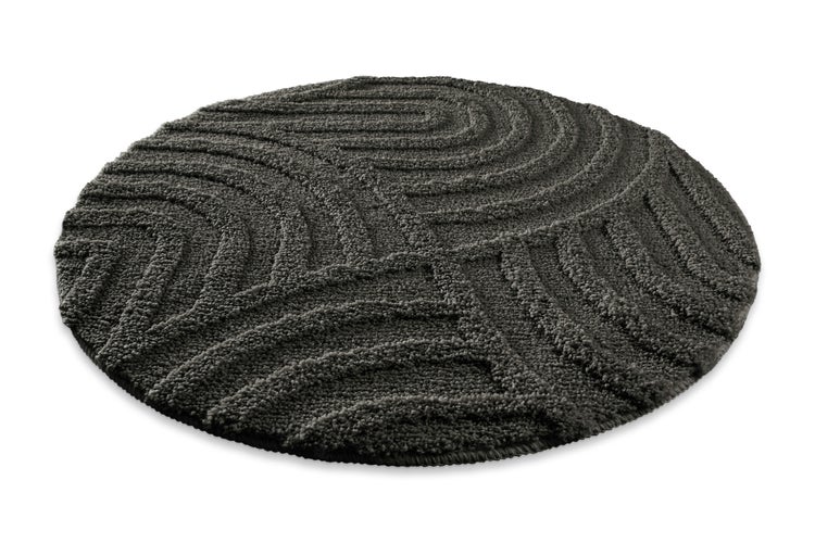 Runder Badeteppich in Dunkelgrau mit reliefartigem Wellenmuster aus weichem Material.