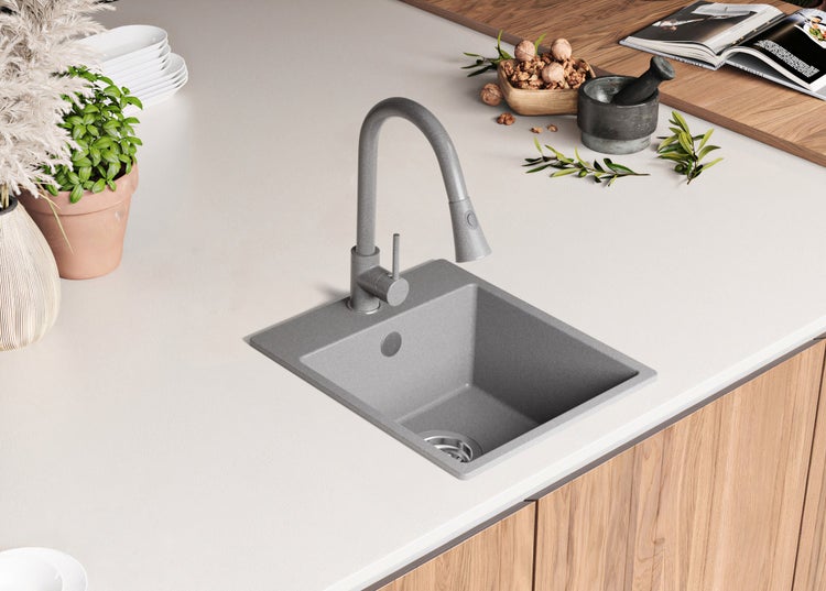 Küchenspüle aus Stein mit Wasserhahn in einer hellen Küche.