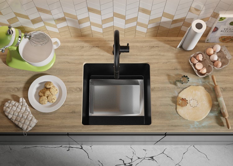 Draufsicht auf eine Küche mit Spüle, Armatur, Teig, Ausstechformen, Eiern und Küchenmaschine