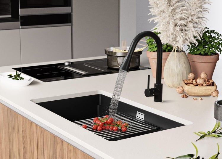 Spüle mit Abtropfgitter, Armatur und abgewaschenen Tomaten in einer modernen Küche