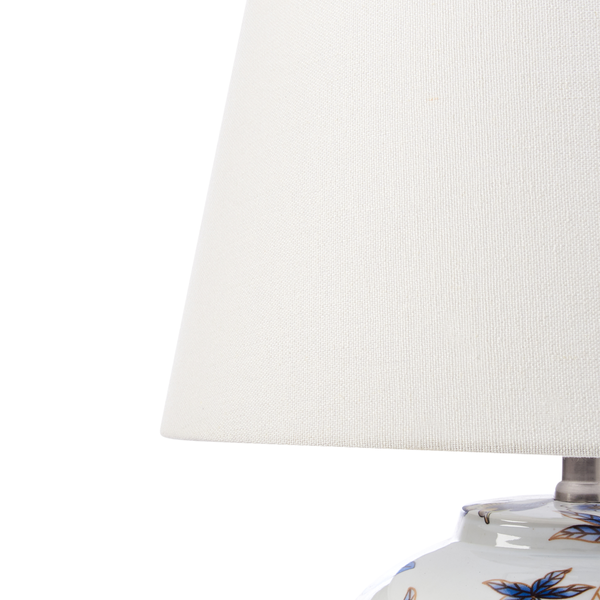 Detailaufnahme einer Tischleuchte mit Textillampenschirm und floralem Muster auf dem Lampenfuß.