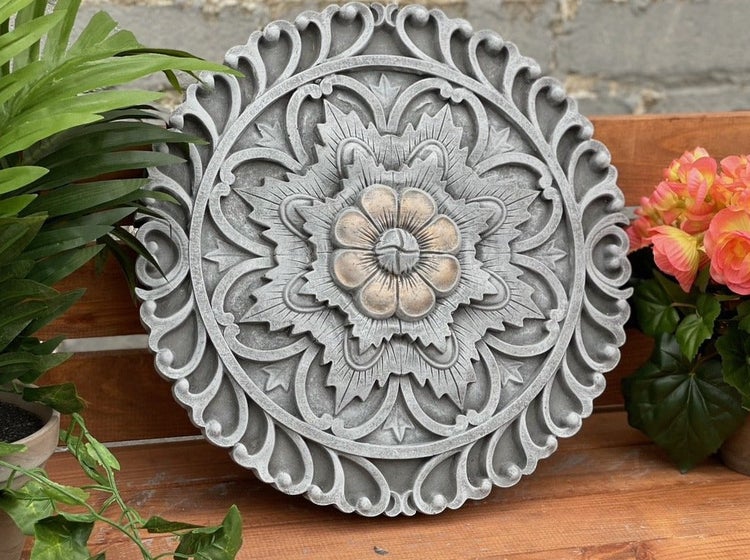 Dekorative Wandplatte aus Stein mit floralem Ornamentmuster und zentraler Blüte für die Innen und Außendekoration.